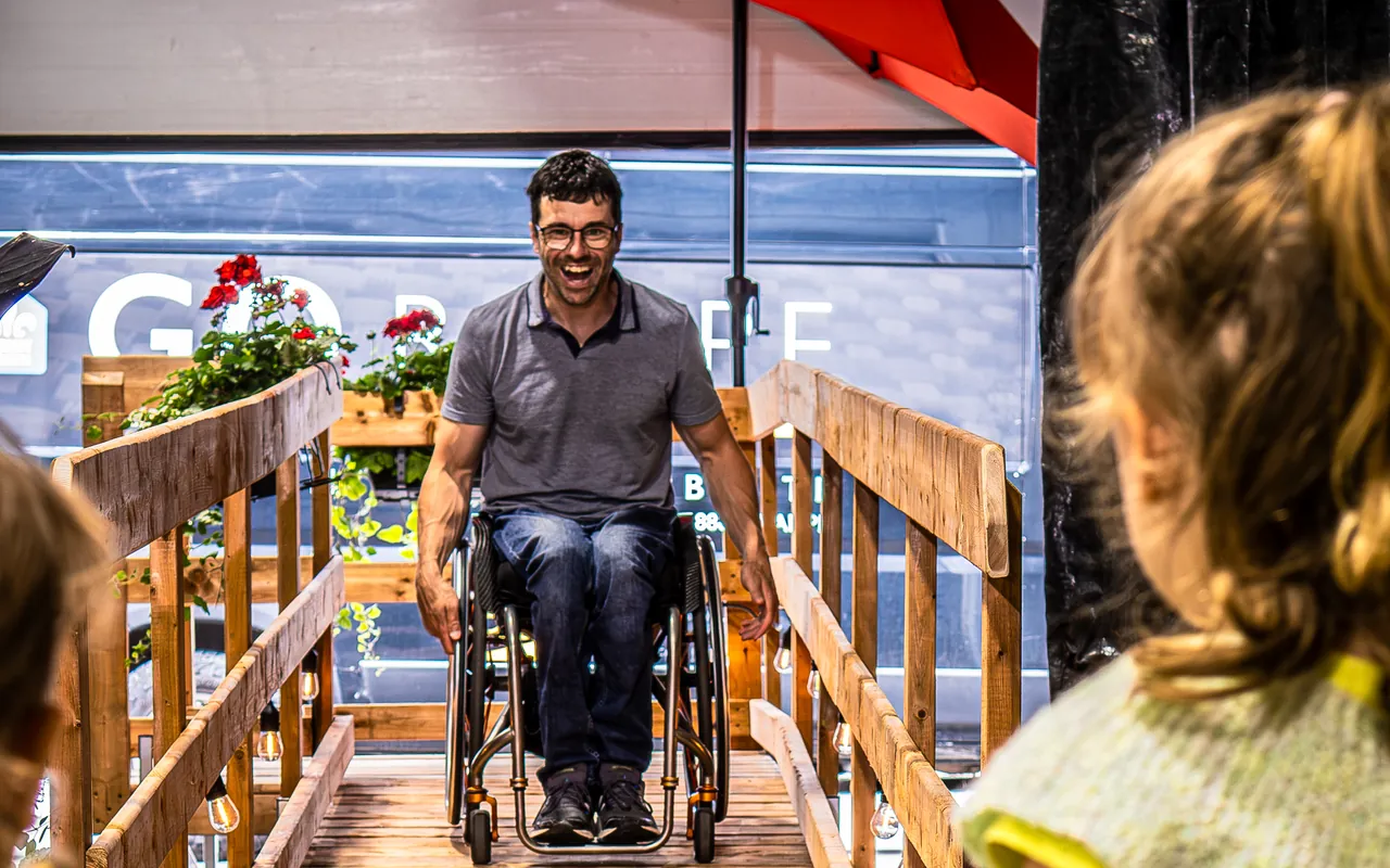 Homme en fauteuil roulant descendant sa rampe de bois Go Rampe vers ses enfants