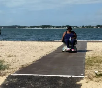 Personne en fauteuil roulant sur un tapis d’accès à la plage